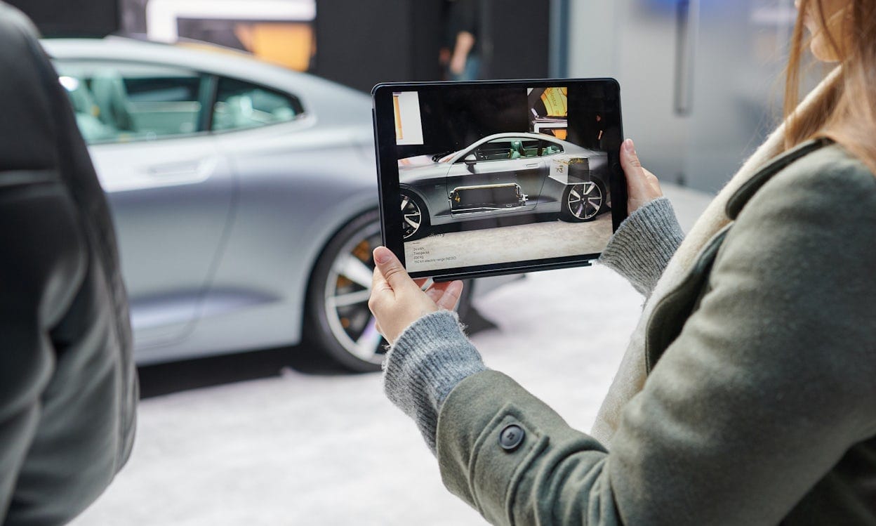 A metallic Polestar 1 in the background being photographed with a tablet