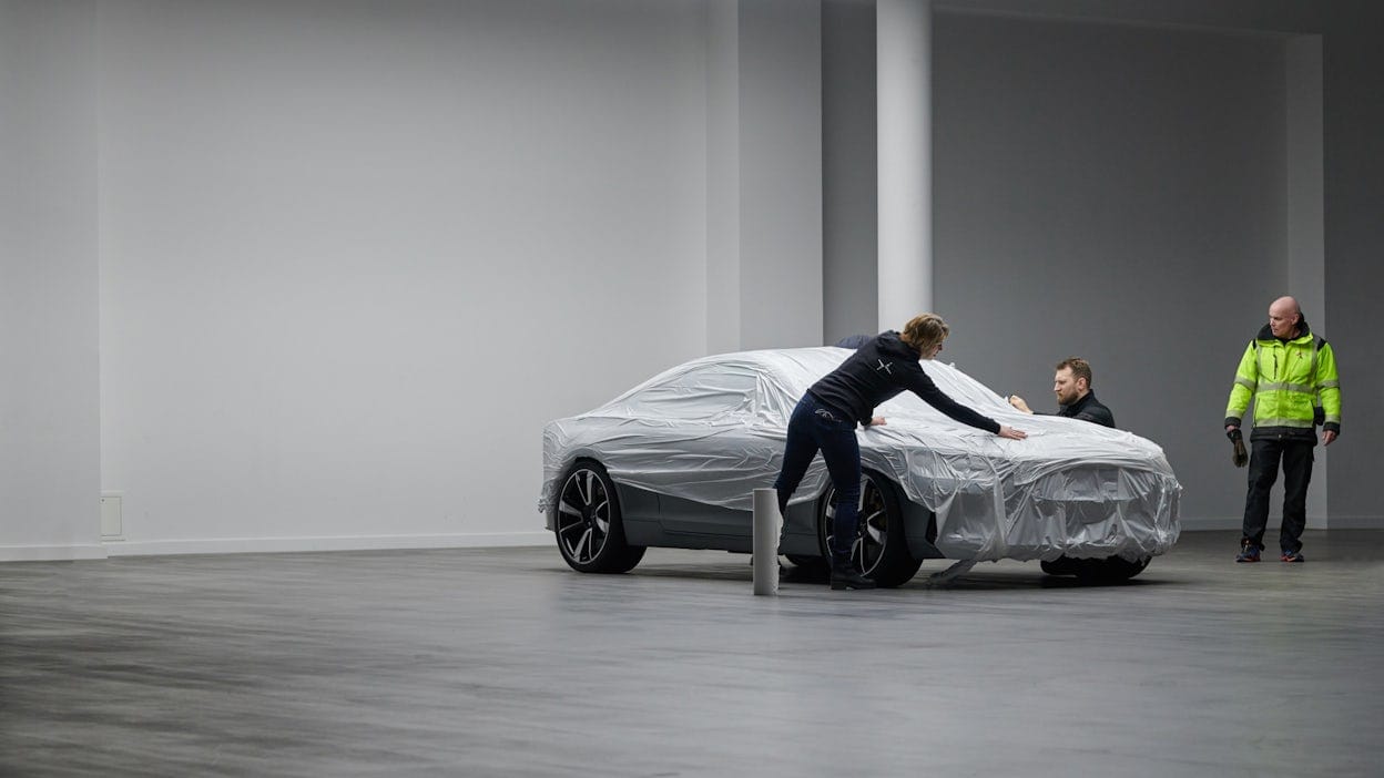 A Polestar covered in protective plastic in a white and grey room