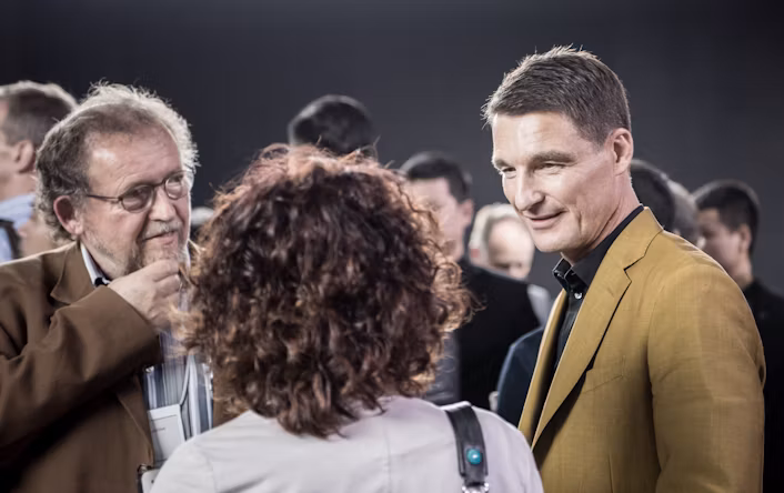 Thomas Ingenlath speaking to two people at an event.