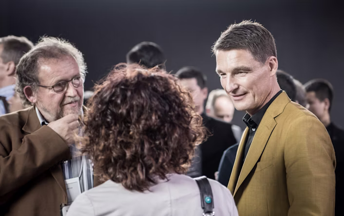 Thomas Ingenlath speaking to two people at an event.