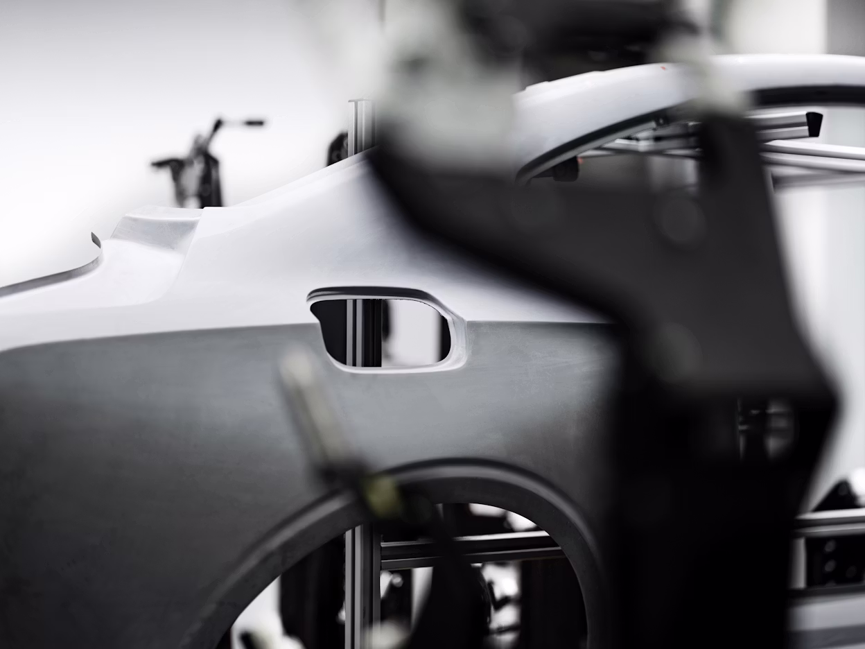 Unfinished Polestar car frame with structural details in focus, blurred workshop equipment in the background.