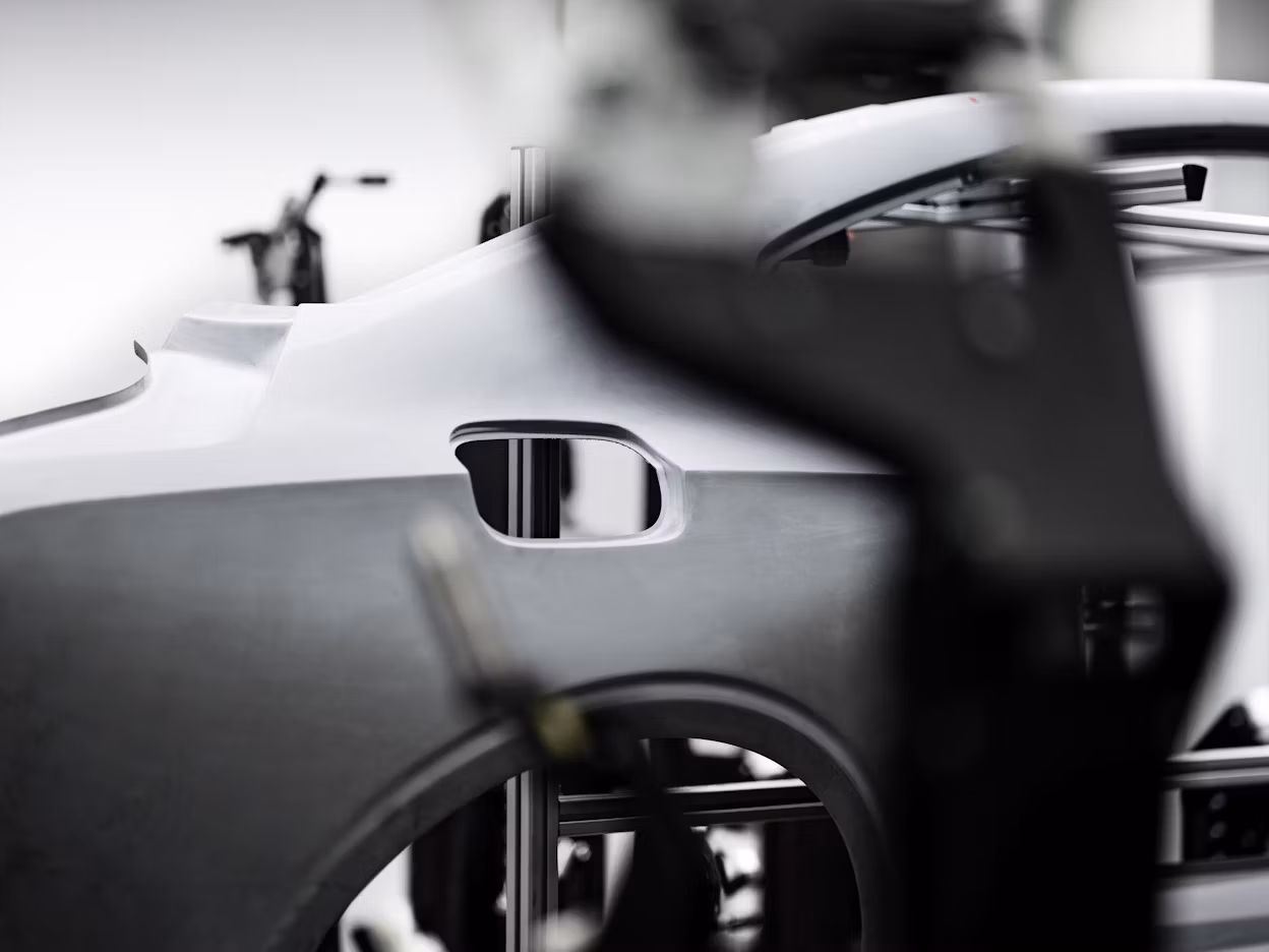Unfinished Polestar car frame with structural details in focus, blurred workshop equipment in the background.
