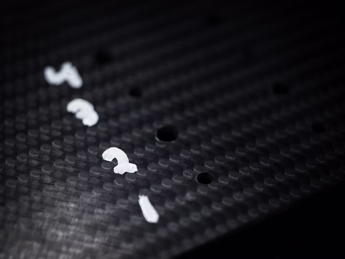 The numbers one to four written on black carbon fibre.