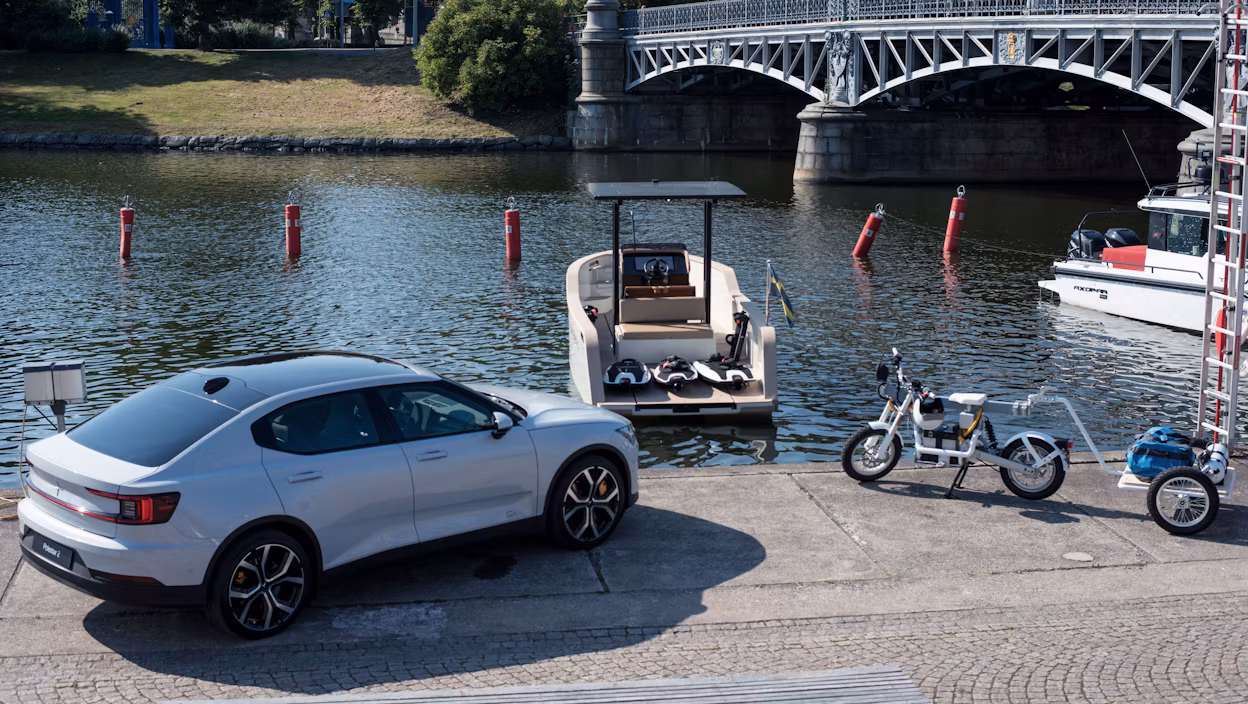 Electric boat, electric motorbike and a Polestar 2 at a dock.