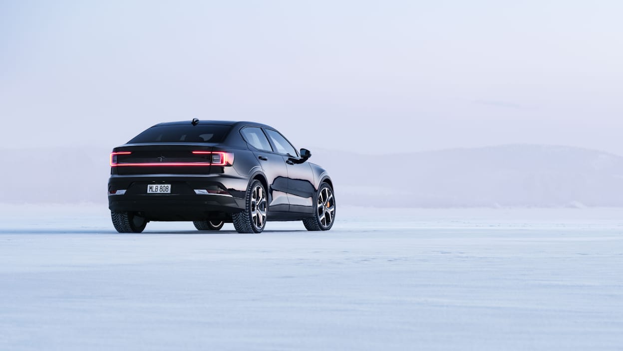 Back view of a black Polestar 2 driving on ice.