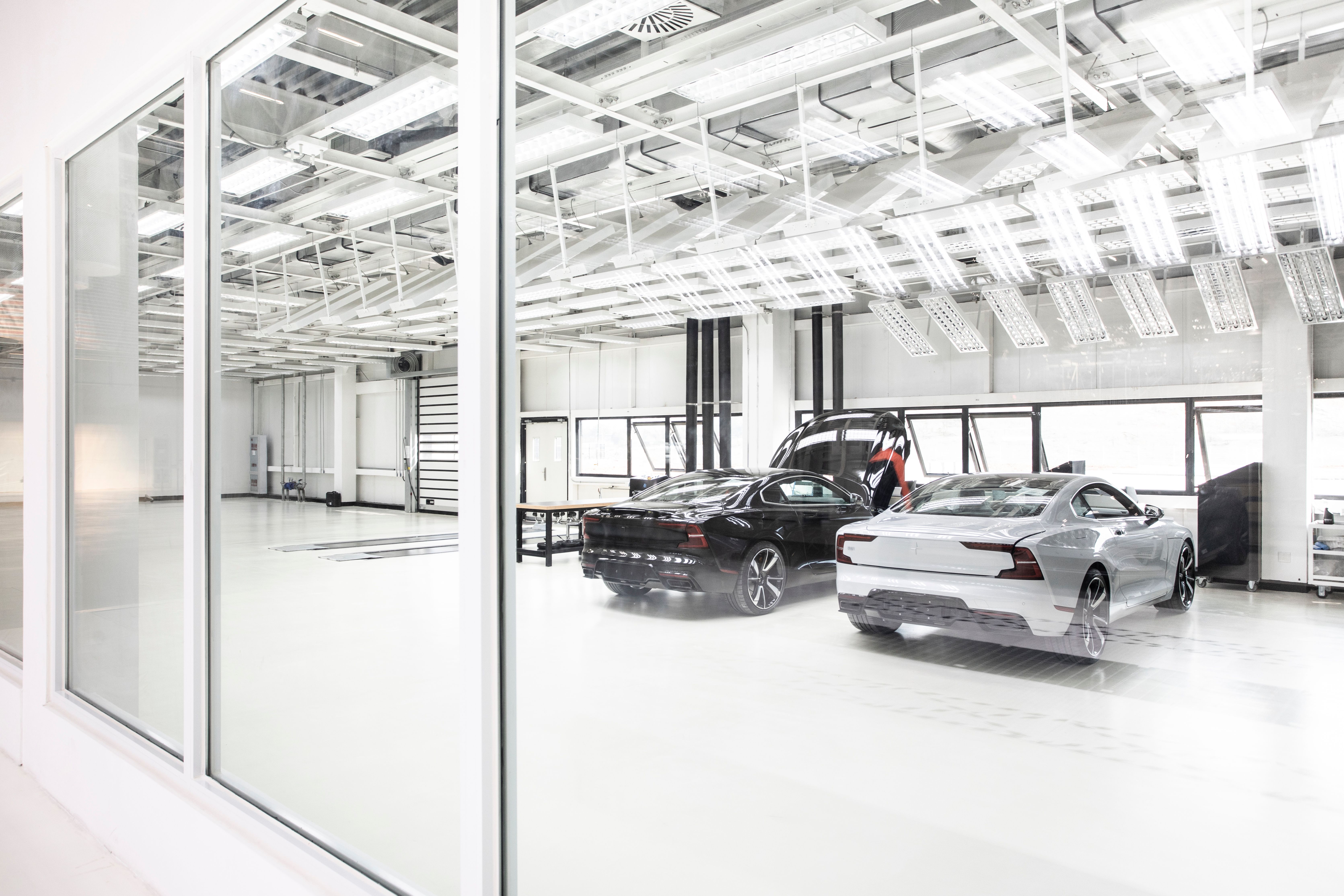 One Black and one white Polestar 2 parked inside a factory