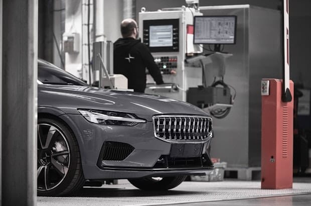 Grey Polestar 2 parked in service place with a man in a black hoodie in the back 