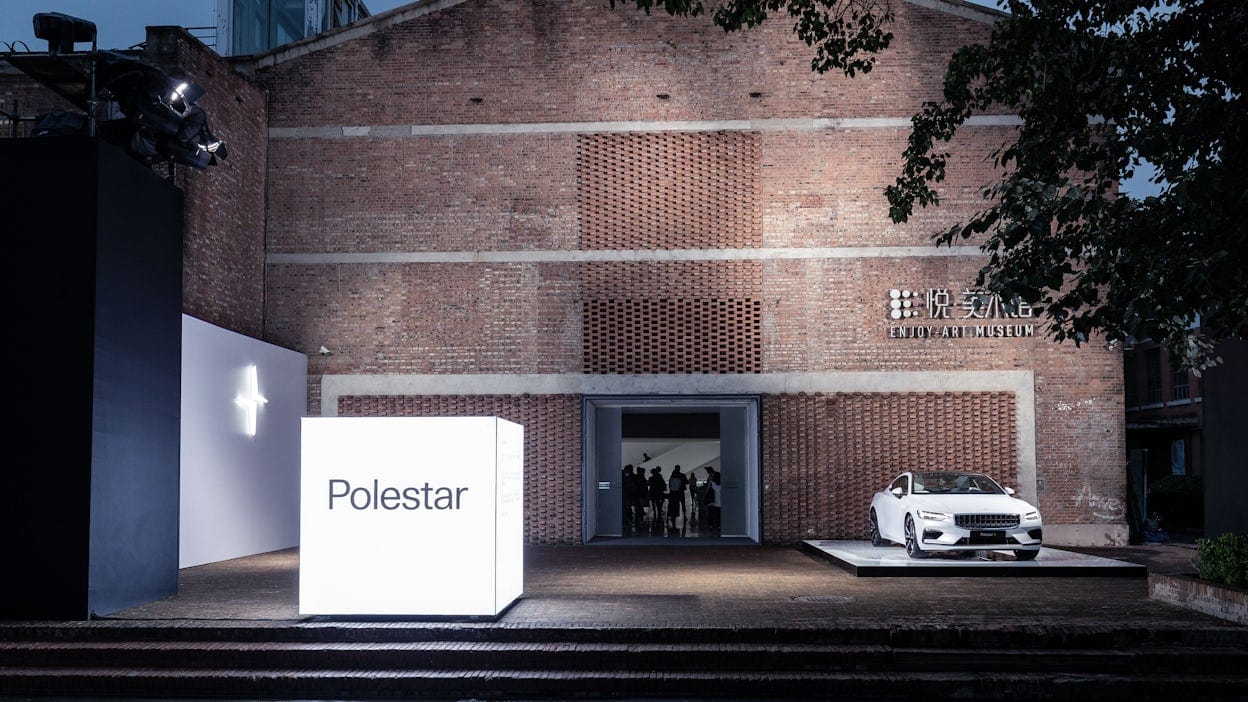 White Polestar and a Polestar sign outside a brick building