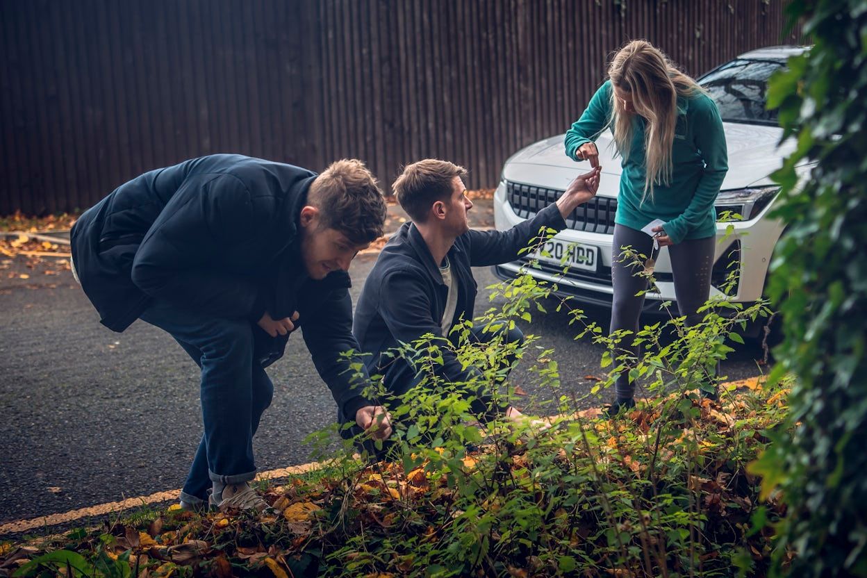 Kirk Haworth, Finnian Casey and Gemma Tadman foraging for mushrooms with a white Polestar 2 parked behind them.