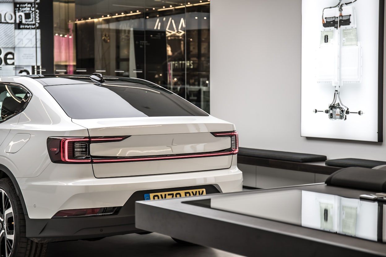 The rear of a white Polestar 2 on display in a Polestar space.