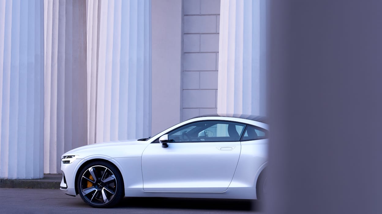 A white Polestar in front of a white brick wall