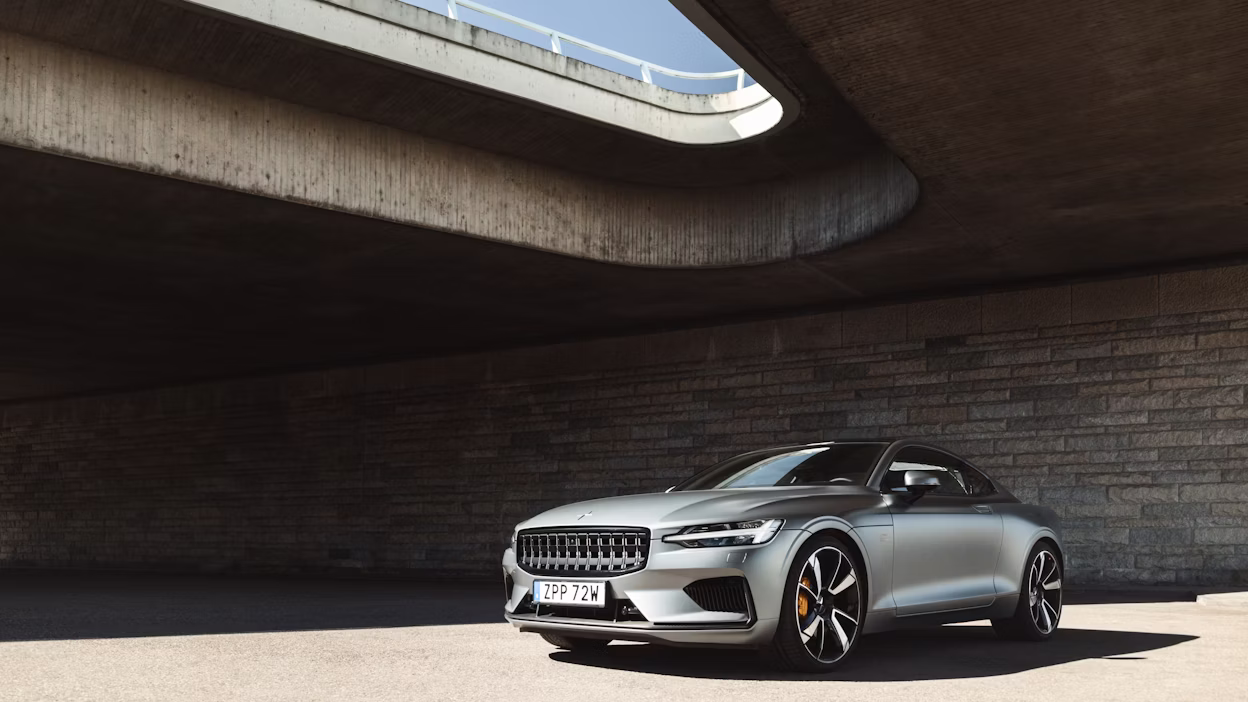 A silver Polestar 1 parked under a bridge.