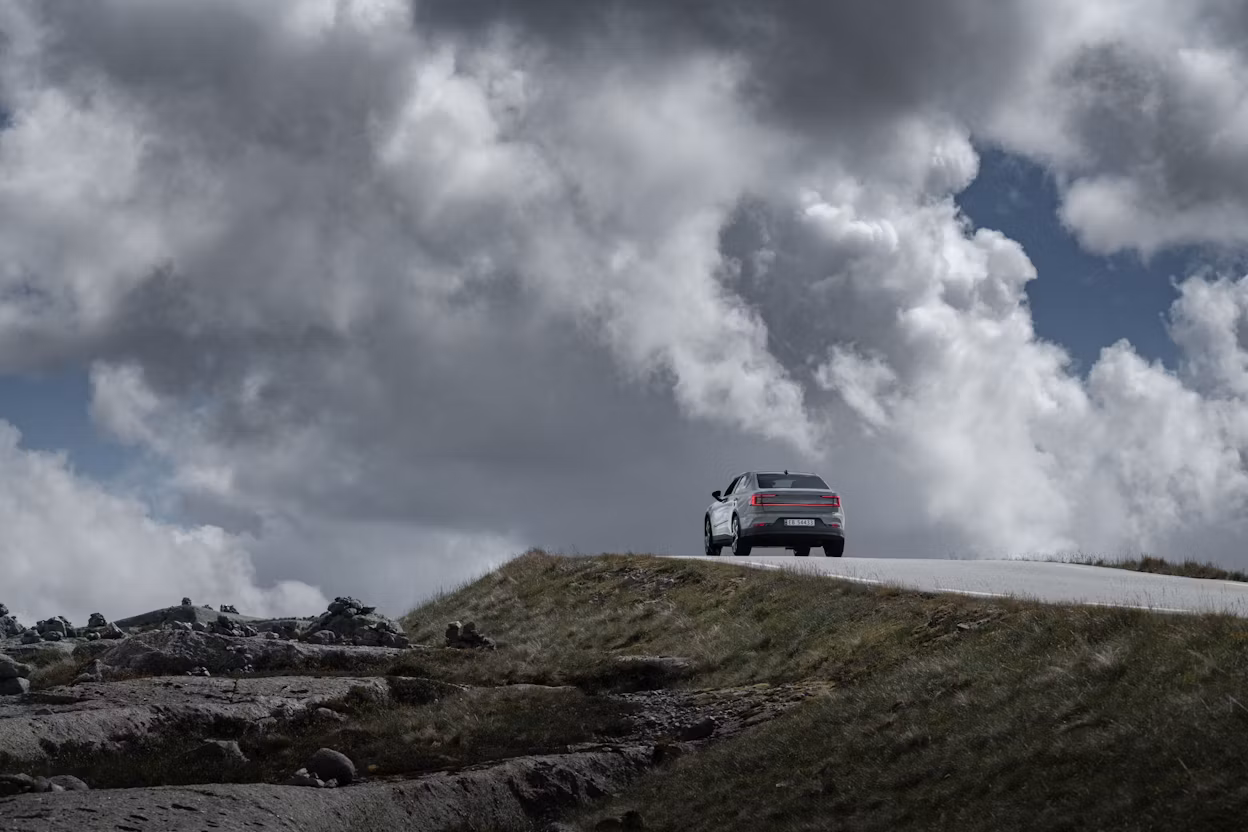 Polestar 2 driving on a hill road on a cloudy day.