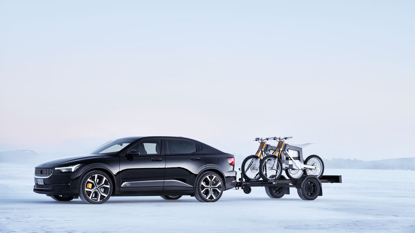 Black Polestar 2 with a trailer with two motorcycles on in winter landscape
