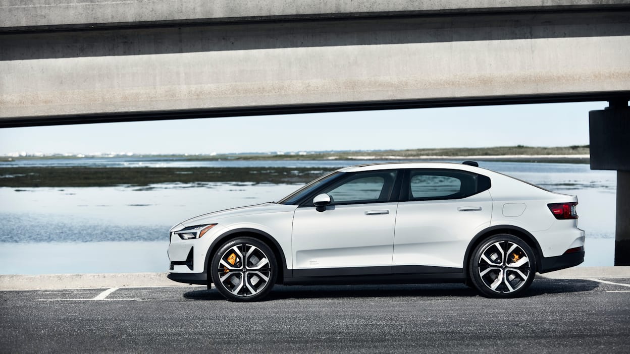 Side view of a white Polestar parked on concrete with a lake in the background.
