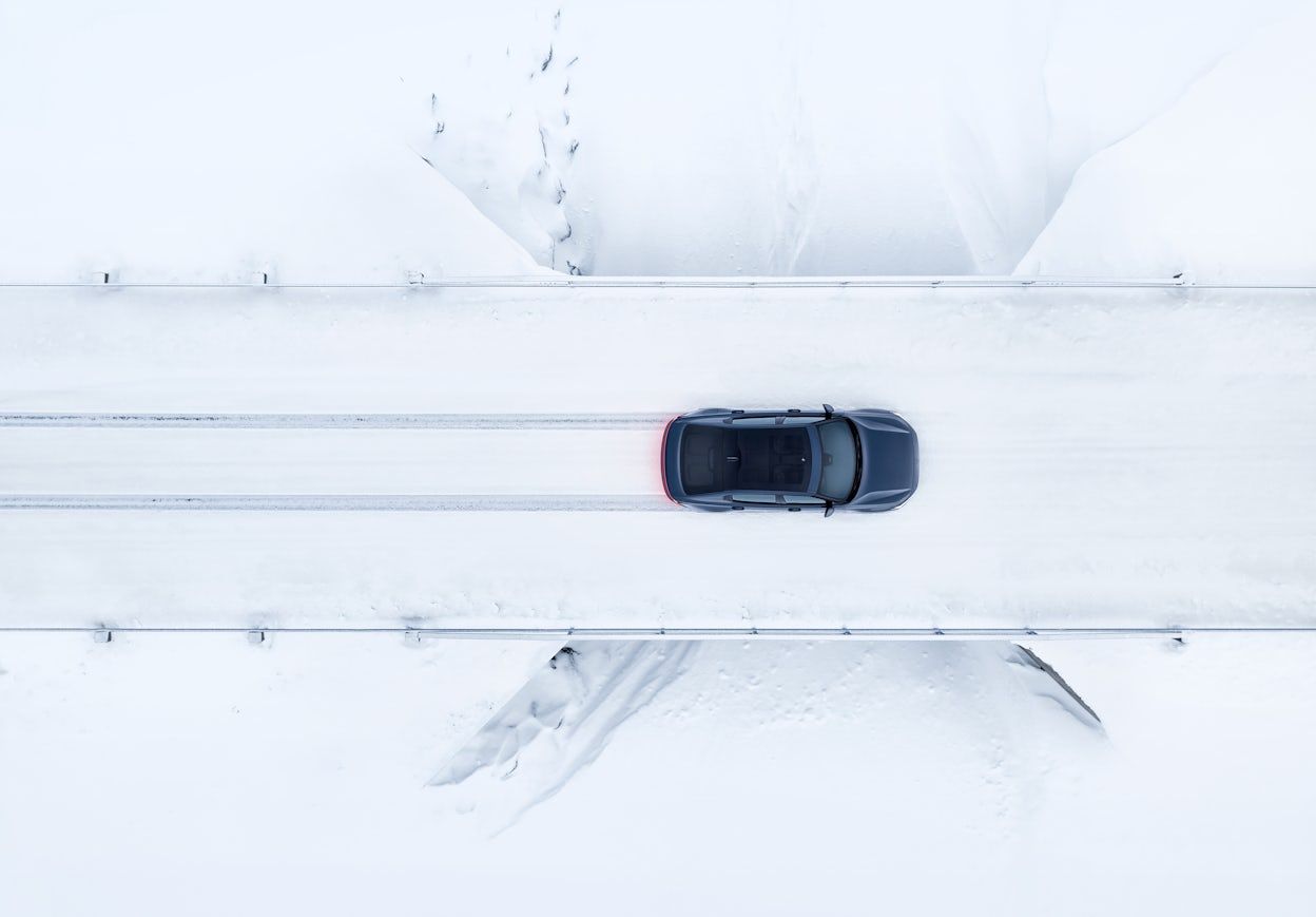 Polestar 2 driving on a snowy road viewed from above.