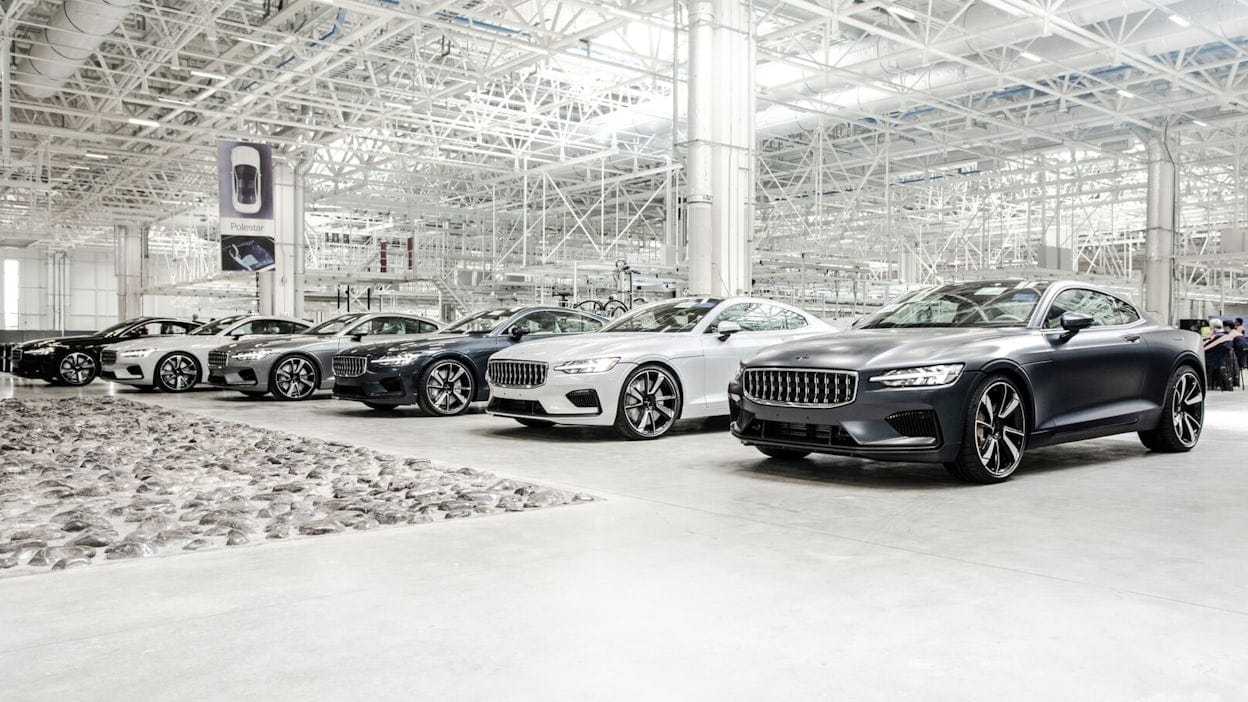Several Polestar 1 in different colours parked in a large warehouse.
