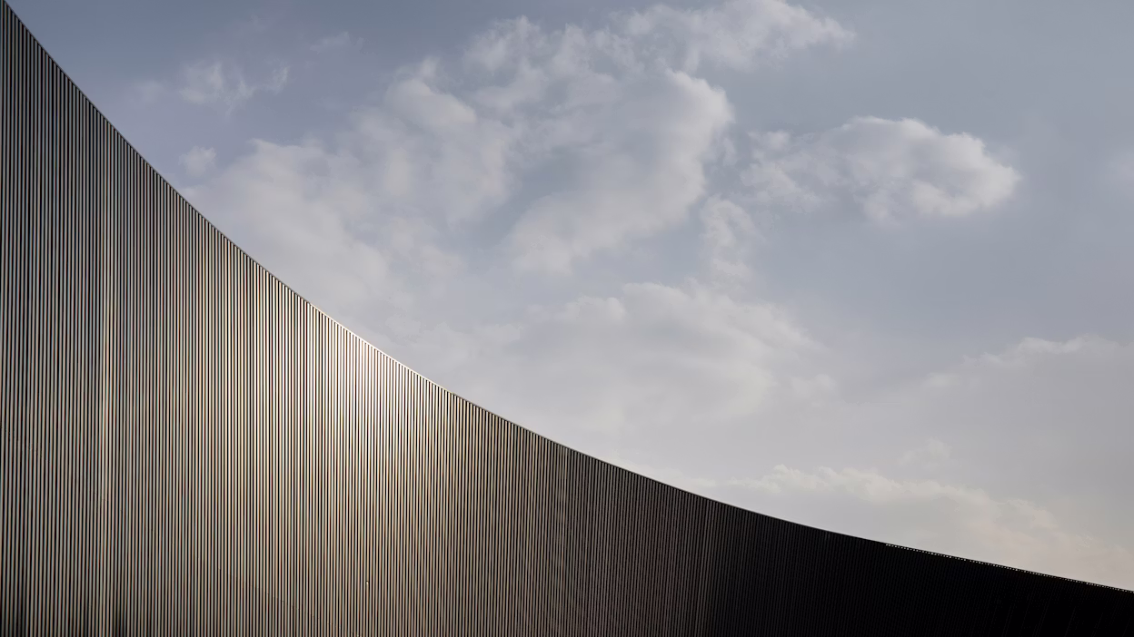 A curved panelled wall with a cloudy sky.