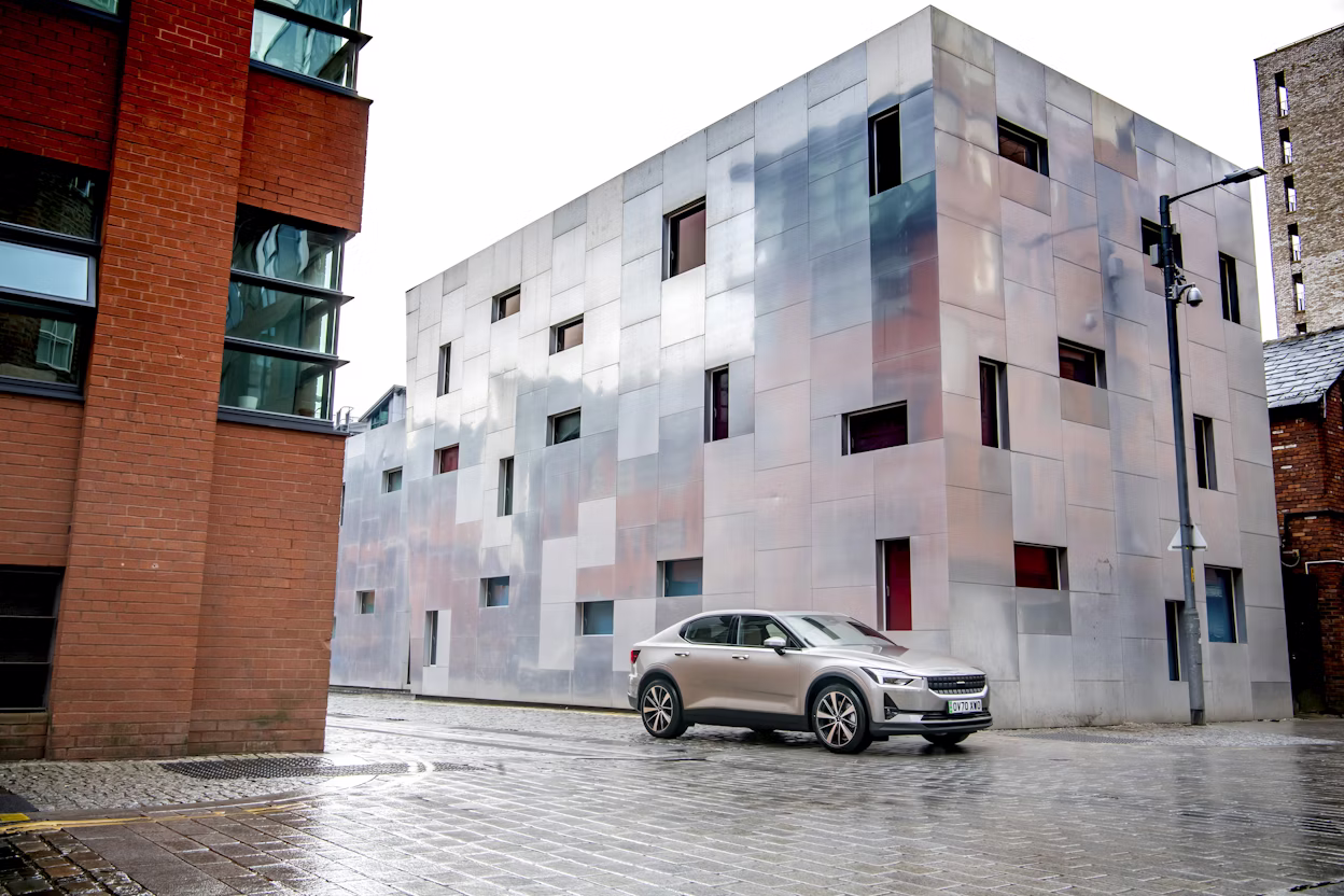 Polestar 2 driving between buildings in a rainy Manchester.