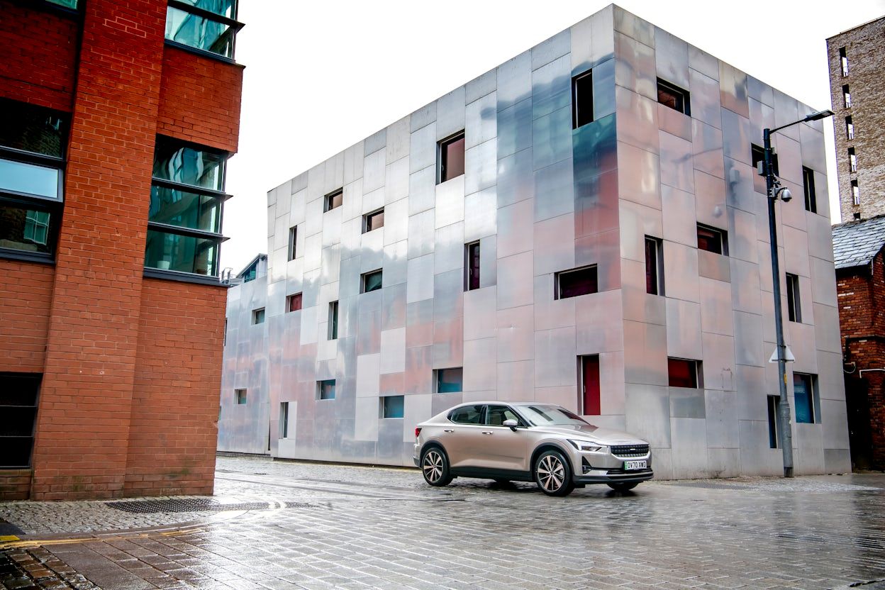 Polestar 2 driving between buildings in a rainy Manchester.