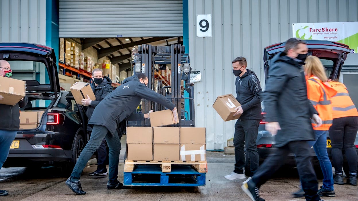 Polestar staff unloading cardboard boxes with donations outside a warehouse.