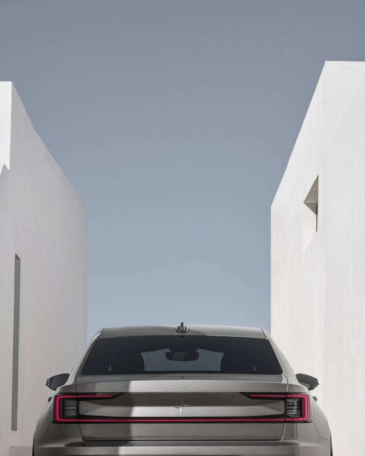 Beige Polestar 2 parked between two white stone buildings 