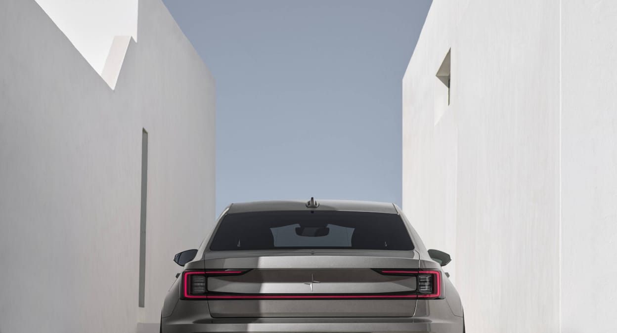 Beige Polestar 2 parked between two white stone buildings 