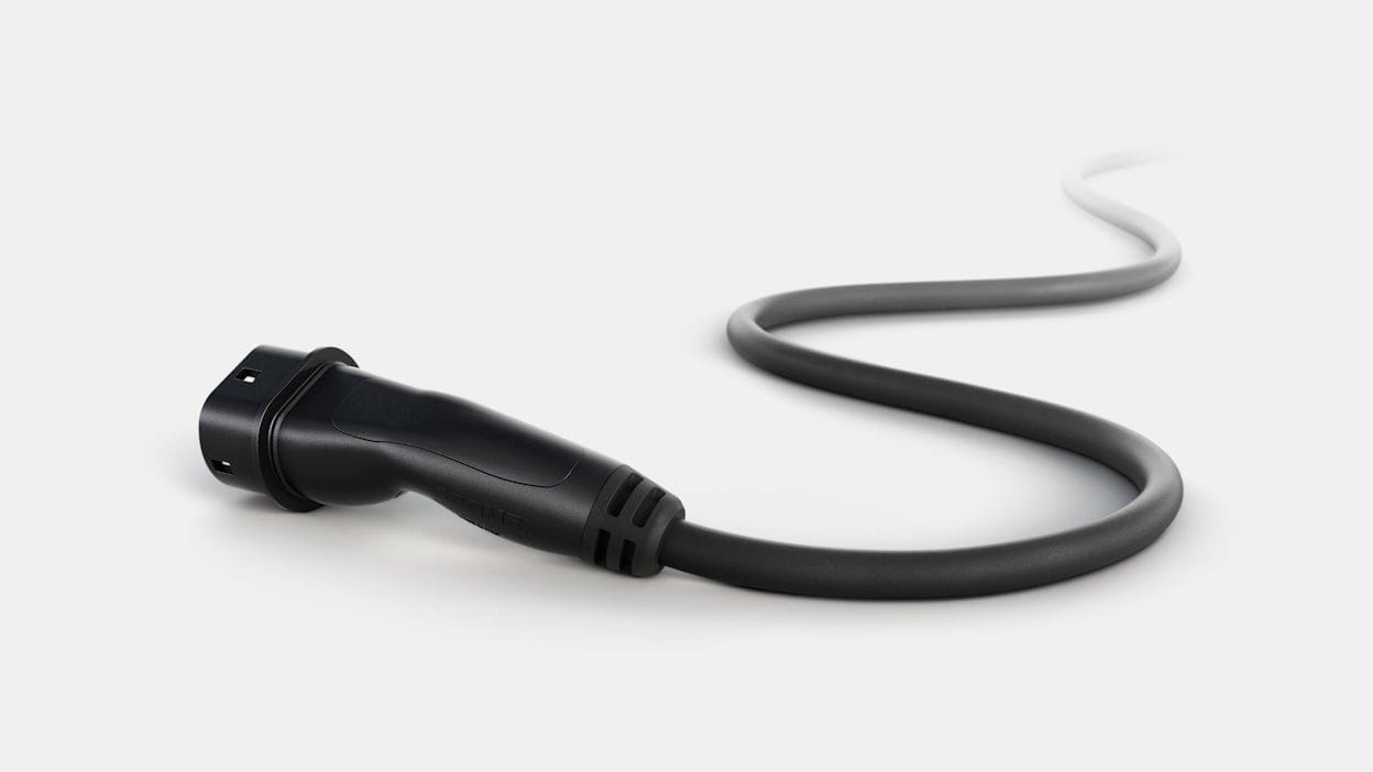 Black EV charging cable lying on a white surface