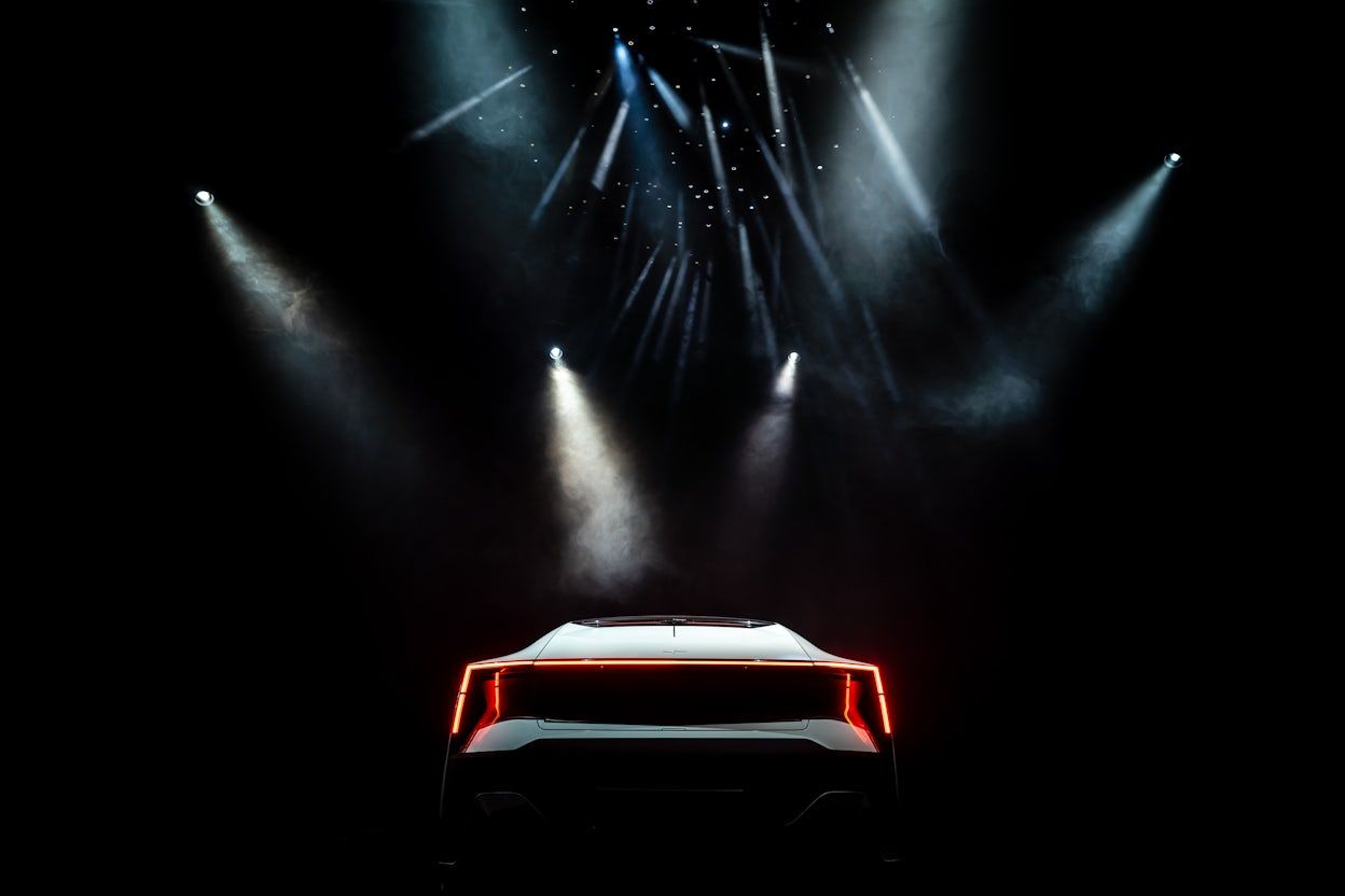 Back view of a Polestar with illuminated brake light parked in a room full of spotlights.