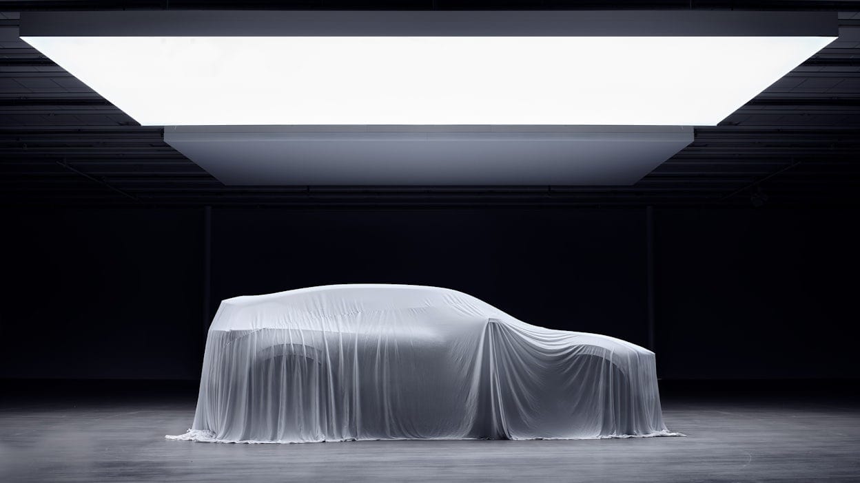 A Polestar 3 covered under a sheet in an empty warehouse.