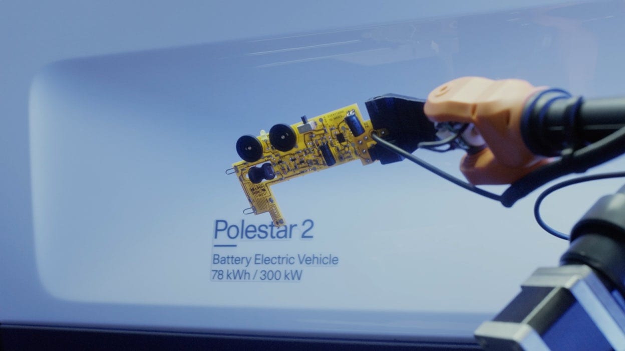 Robot arm in front of a white wall with the text Polestar 2, Battery Electric Vehicle.