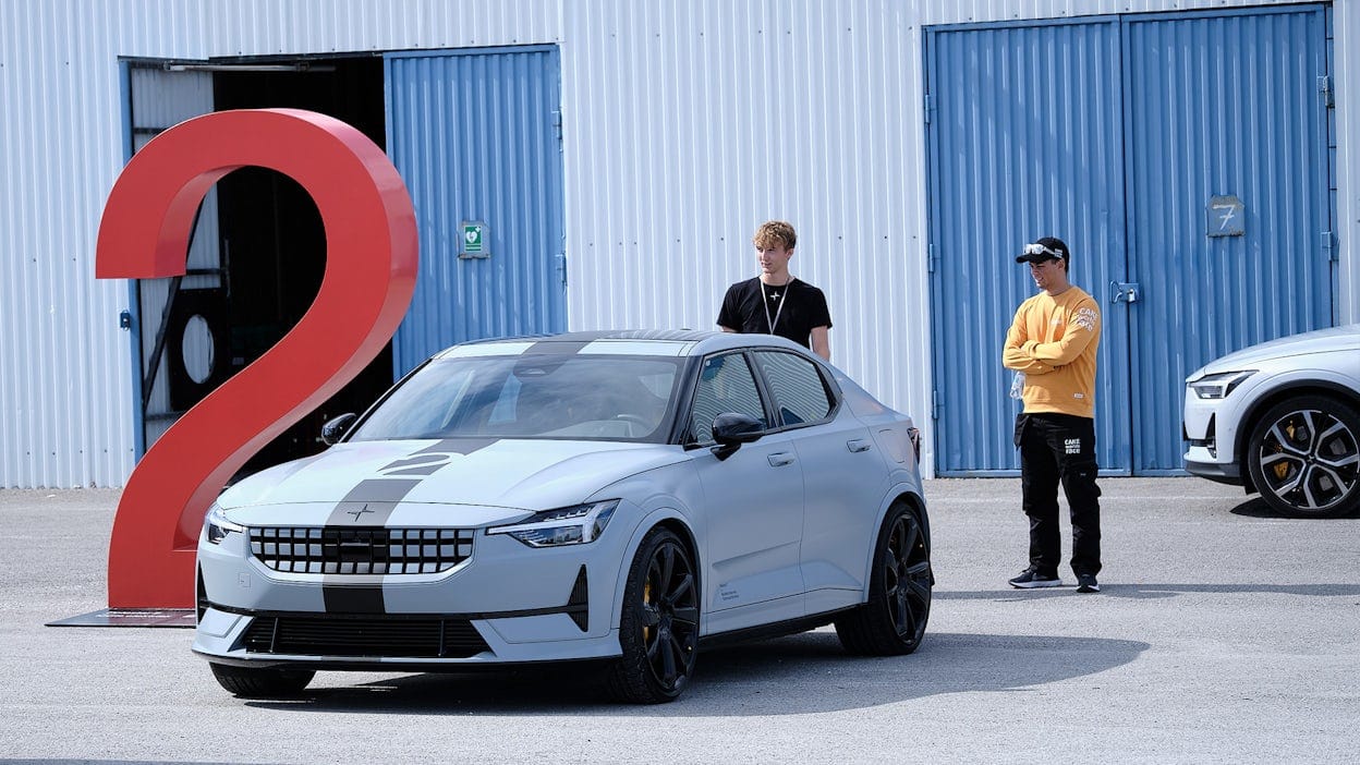 Polestar 2 parked in front of a garage with two men inspecting it from behind