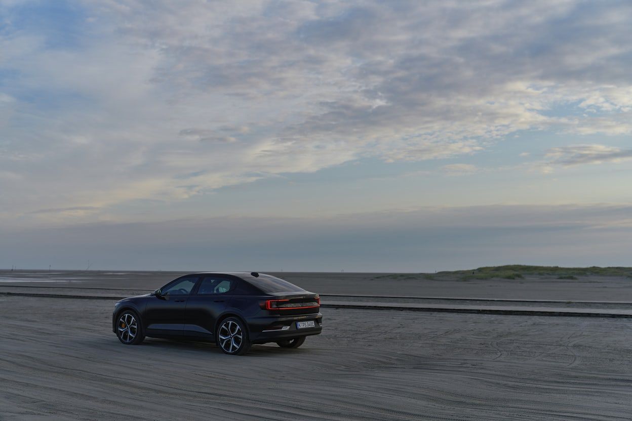 Black Polestar 2 driving on a beach.