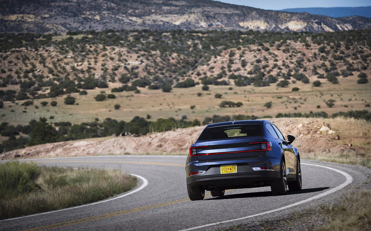 Back view of a blue Polestar 2 on the road in the Rocky Mountains.