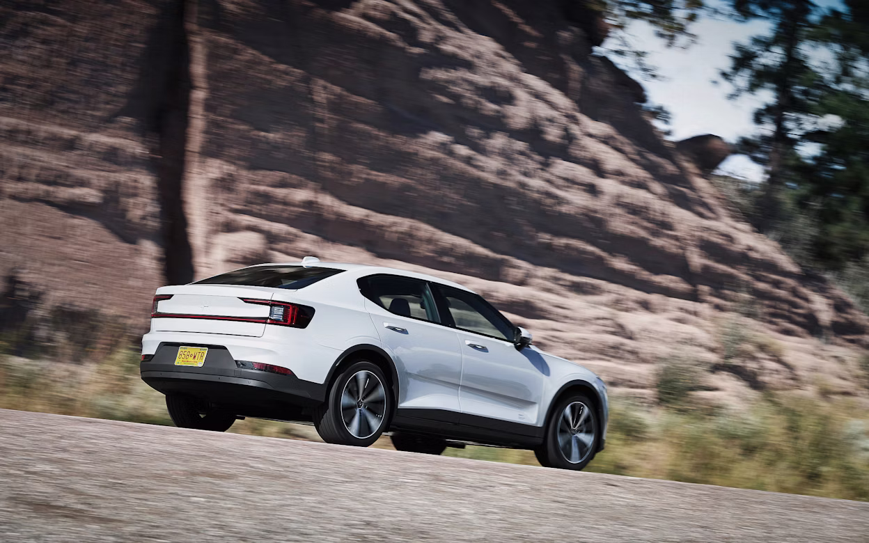 Side view of a white Polestar 2 on the road with a blurry background.