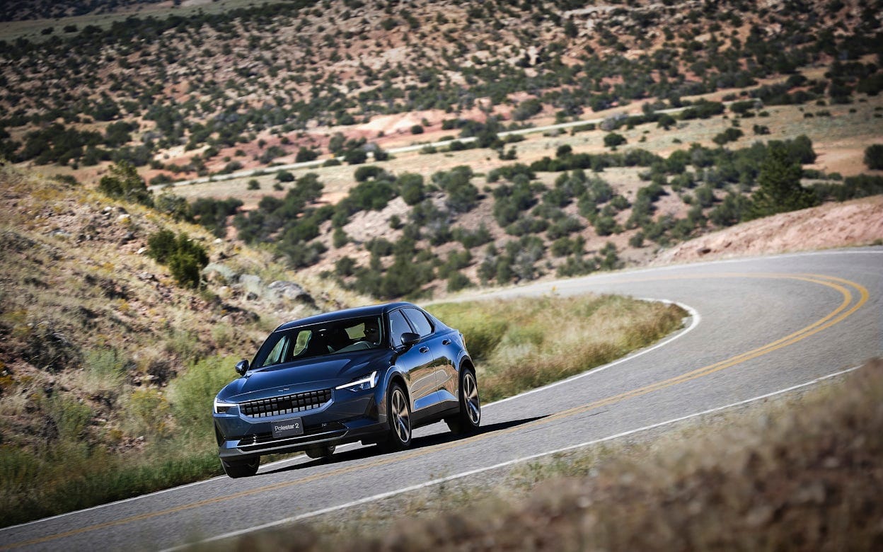 Front view of a blue Polestar 2 on the road surrounded by dry nature in New Mexico.