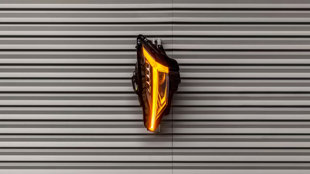 Object symbolising a heart with yellow led-light in the middle amidst a metallic background.