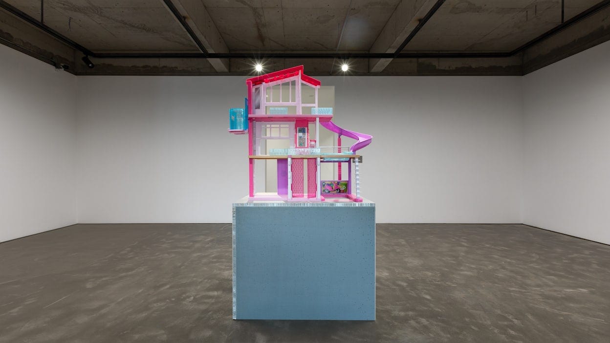 Pink and purple barbie house displayed in an empty industrial room