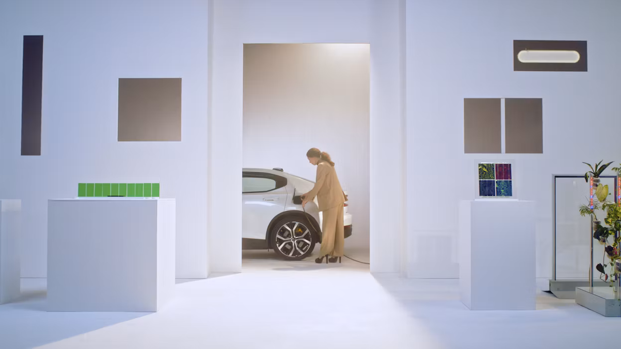 Woman standing next to a Polestar and plugging in the charger.