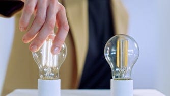 Two light bulbs with a person turning one of them on.