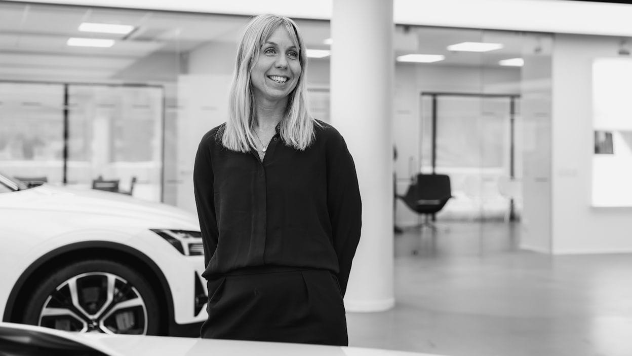 Blonde woman smiling whilst standing next to a Polestar car