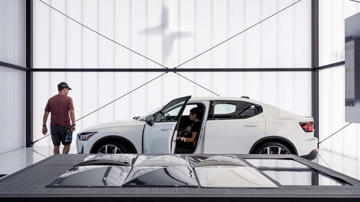 Person trying a white Polestar 2 in a minimalistic show space.