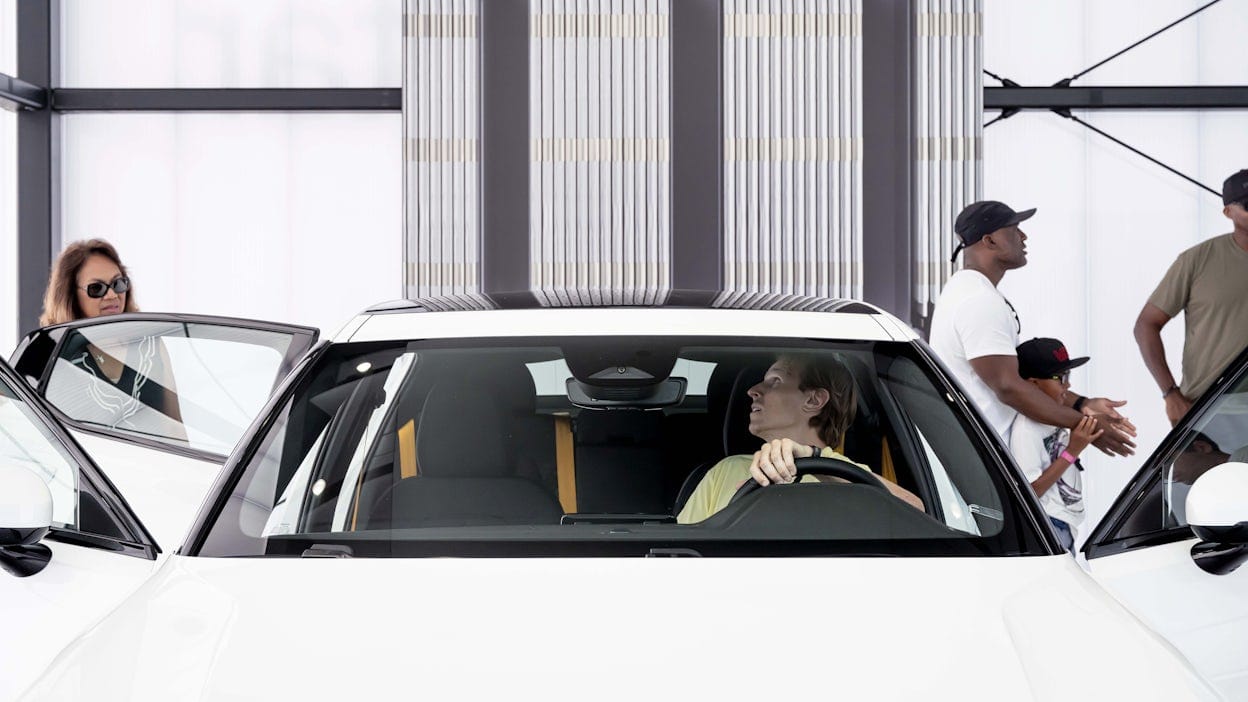 Person sitting behind the wheel in a white Polestar inside a warehouse.