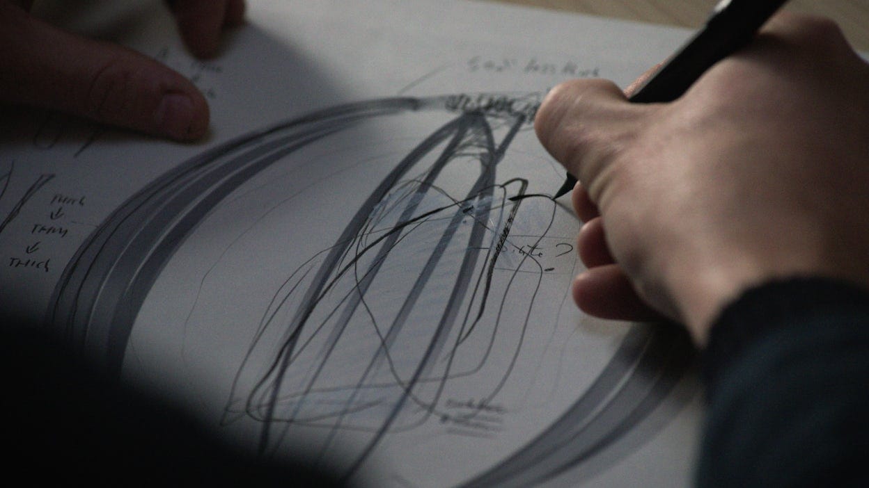 Close up of a man's hands doing sketches on a paper.