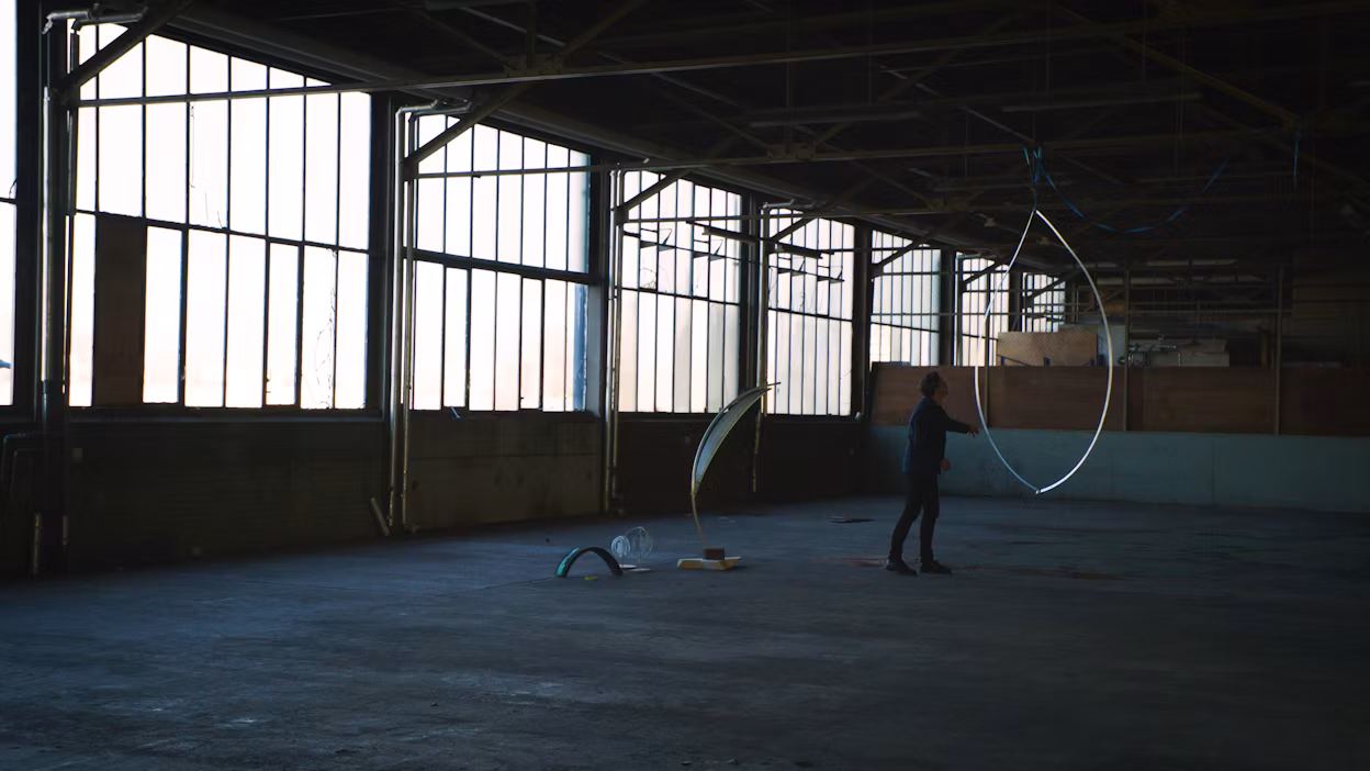 Man standing next to a blade model of We Harvest Wind, in a warehouse.