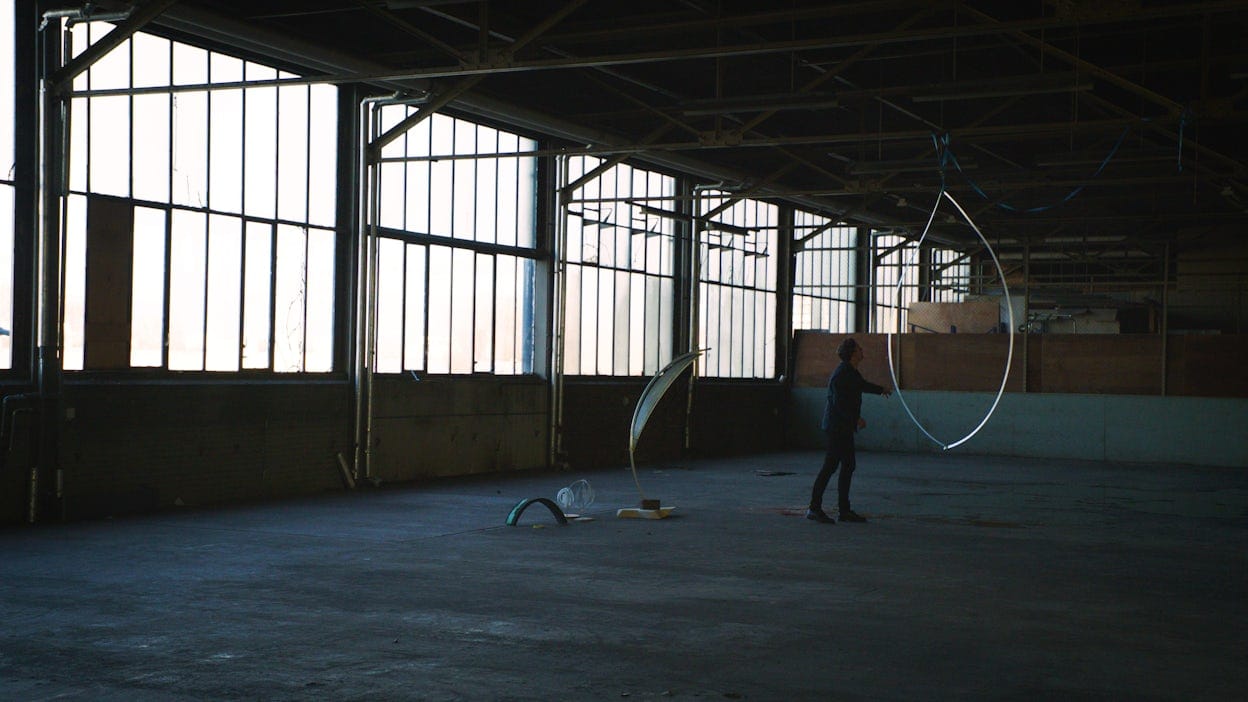 Man standing next to a blade model of We Harvest Wind, in a warehouse.