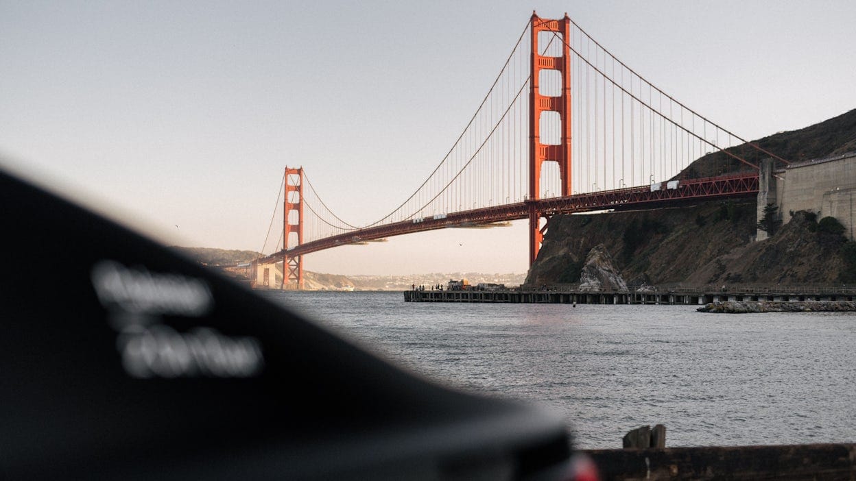 A blurry Polestar 2 positioned in front of the Golden Gate bridge.
