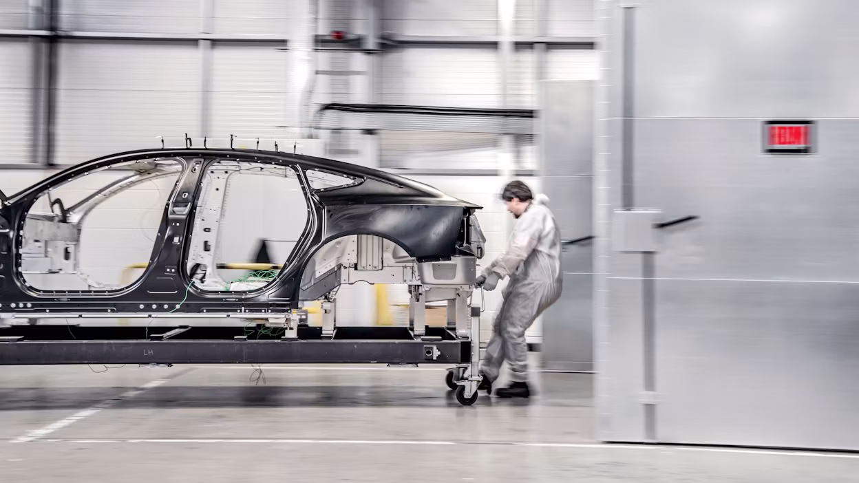 Worker dragging the bonded aluminium unibody of Polestar 5 in a workshop.