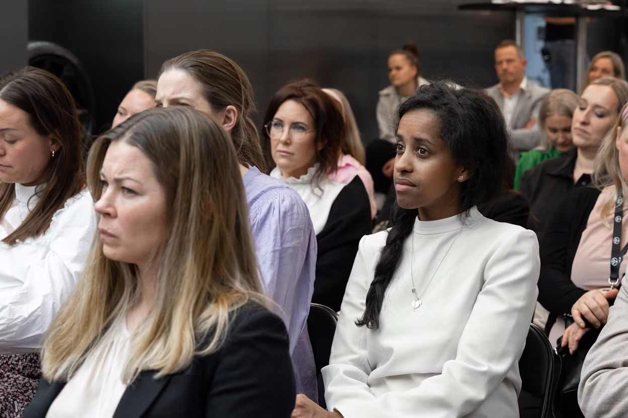 Group of people seated indoors, some wearing formal attire.