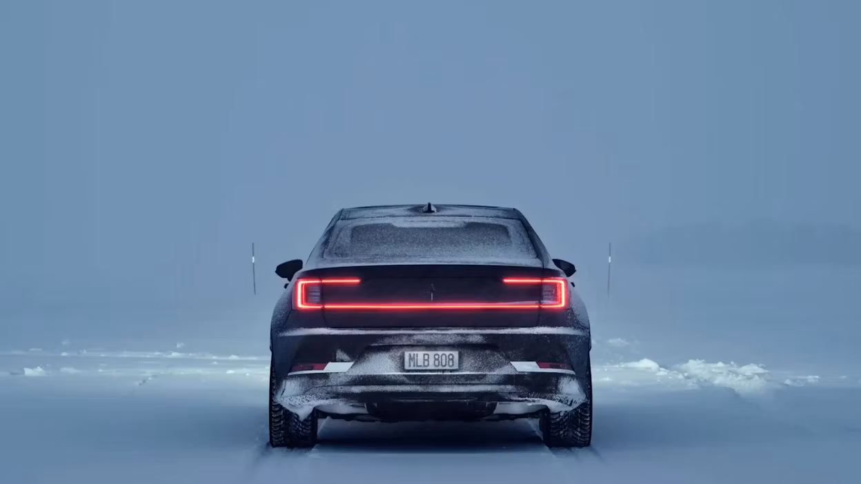 Rear view of a Polestar car on a snowy road with taillights illuminated.
